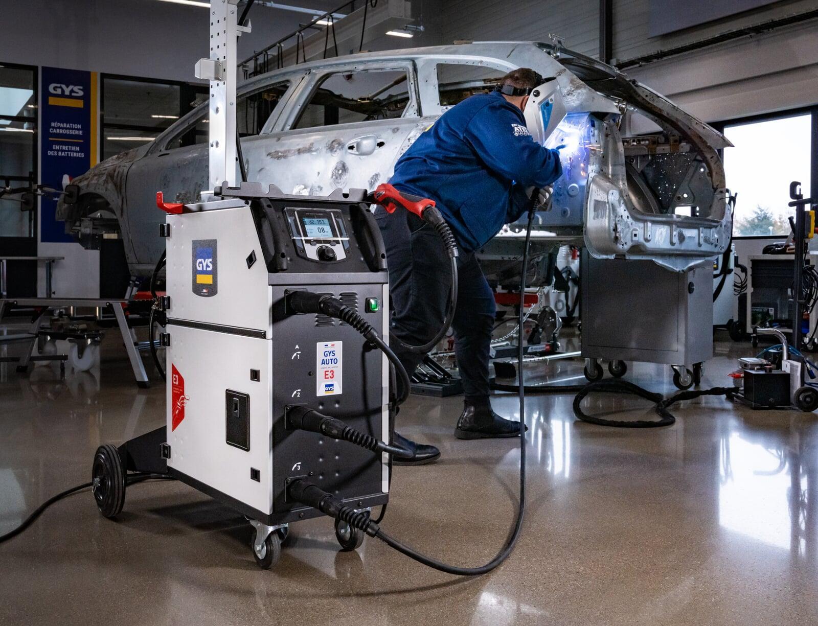 The GYS AUTO P3 alongside a stripped body shell in a collision shop